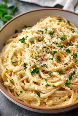 Plate of cheesy garlic parmesan spaghetti topped with parsley and parmesan cheese.