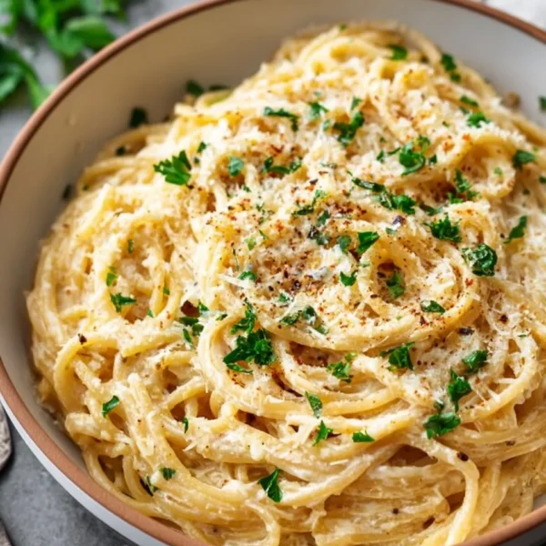 Plate of cheesy garlic parmesan spaghetti topped with parsley and parmesan cheese.