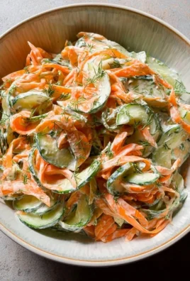 Creamy cucumber and carrot salad in a bowl, garnished with herbs.