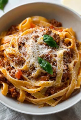 Creamy Fettuccine Bolognese topped with fresh herbs and cheese