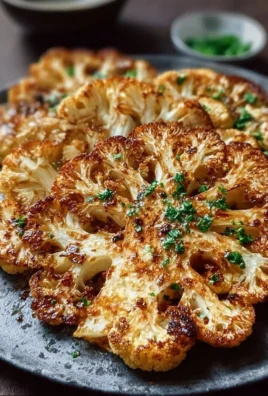 Crispy baked cauliflower steaks served on a plate with garnishes