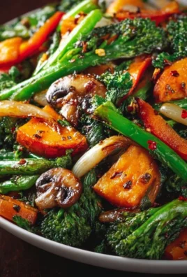Plate of colorful sautéed vegetables including broccoli, bell peppers, and carrots