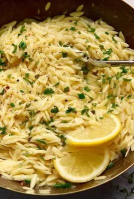 Delicious lemon orzo pasta served with fresh herbs and lemon slices.