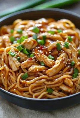 Sticky garlic chicken noodles served in a bowl with fresh herbs and vegetables.