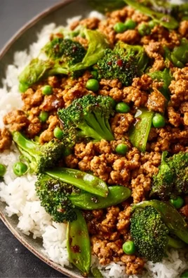Plate of teriyaki ground turkey with broccoli and peas, garnished with sesame seeds