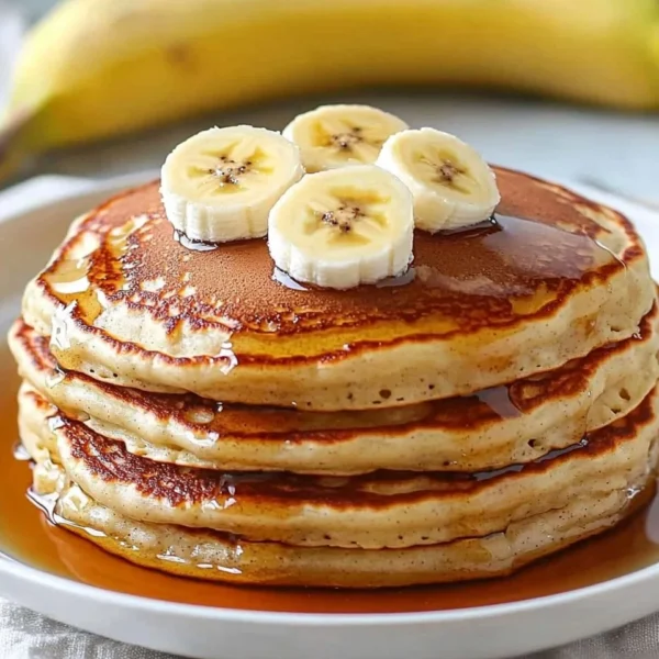 Fluffy homemade banana pancakes stacked with syrup and fresh bananas