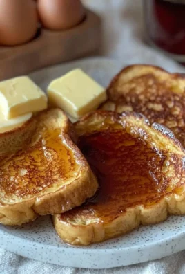 Delicious French toast topped with fresh berries and syrup served on a white plate.