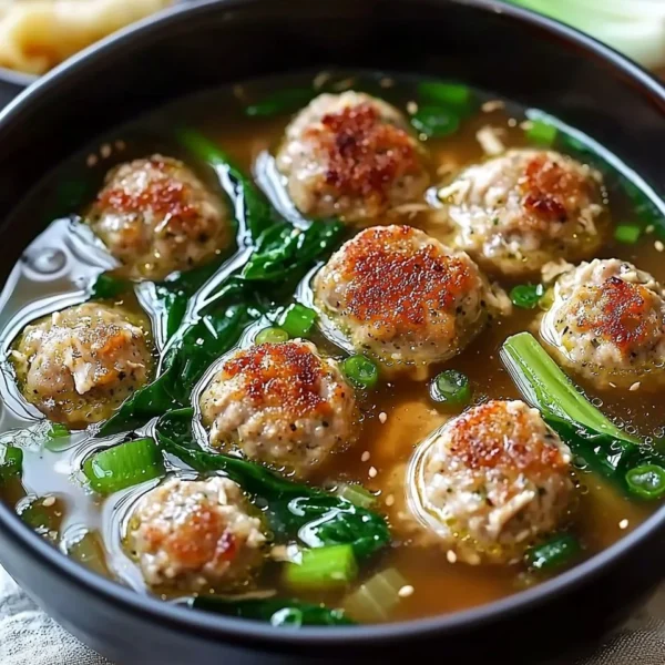 Comforting ginger chicken meatball soup with bok choy in a bowl