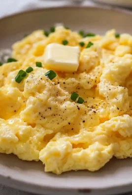 Fluffy scrambled eggs served on a plate with herbs and spices.